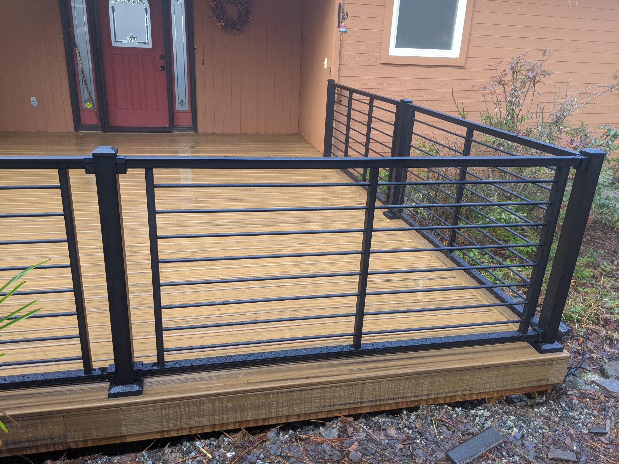 Front patio-style trex deck featuring black metal railing