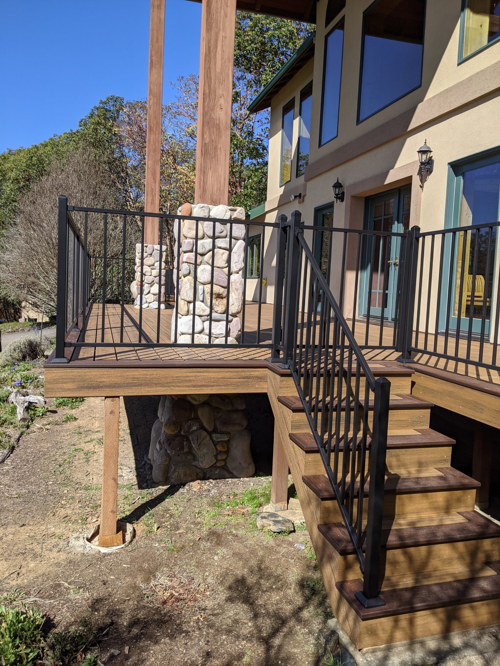 Deck with rock house posts and black metal railing